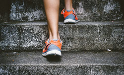 The lower part of two legs running up of a stair, you see gym shoes and the calves.