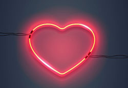 Ett hjärta gjort av röd lysdiod som skiner mot en svart bakgrund.